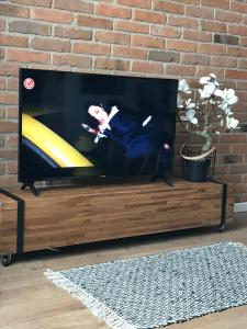 uma televisão de ecrã plano sentada num centro de entretenimento em madeira em SOLE Apartment 2 em Satu Mare