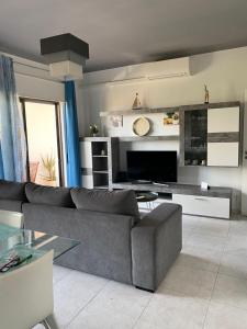 a living room with a gray couch and a television at Refugio Praia da Rocha in Portimão