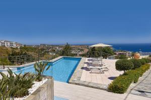 einen Pool mit Stühlen und Meerblick in der Unterkunft Keramos Villa & Apartments in Agia Pelagia