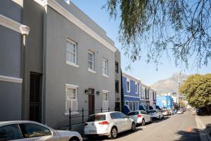 Cape Town的住宿－Purple House Accommodations，停在建筑物旁边的街道上的一排汽车