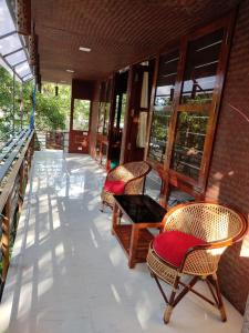 a porch with chairs and tables and windows at Coconut Garden in Cherai Beach