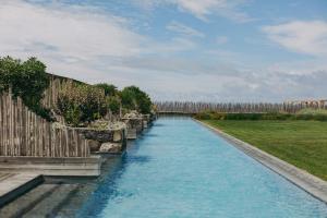 a canal with blue water and a wooden fence at Santa Barbara Eco-Beach Resort in Ribeira Grande