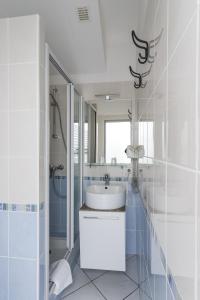 a white bathroom with a sink and a mirror at Hotel Les Palmiers En Camargue in Saintes-Maries-de-la-Mer