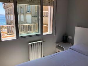 1 dormitorio con cama, ventana y radiador en Hotel Venezuela, en Sanxenxo