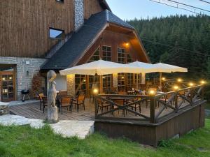a building with a deck with tables and umbrellas at Horský hotel Vidly in Karlova Studánka
