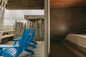 a room with blue chairs on a deck with a bed at Santa Barbara Eco-Beach Resort in Ribeira Grande