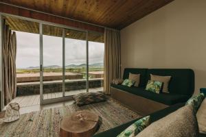 a living room with a couch and a large window at Santa Barbara Eco-Beach Resort in Ribeira Grande