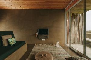 a room with a couch and a tv on a wall at Santa Barbara Eco-Beach Resort in Ribeira Grande