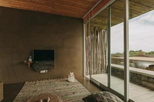 a living room with a tv and a large window at Santa Barbara Eco-Beach Resort in Ribeira Grande
