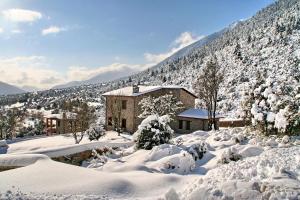 una casa cubierta de nieve frente a una montaña en Menalia Villas & Suites ΚΤΗΜΑ ΚΟΥΜΠΟΥΡΗ, en Levidhion