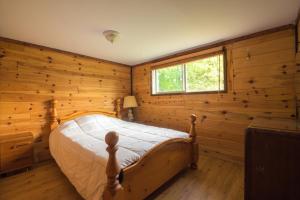 MindenにあるBeautiful 3 Bdrm + Bunkie Waterfront Cottage Near Gull Lakeの木製の部屋にベッド1台が備わるベッドルーム1室があります。