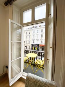 an open window with a view of a table and chairs at Stylish Apartments in Pimlico & Westminster in London