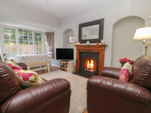 a living room with two leather chairs and a fireplace at Wedgewood Cottage in Leyburn