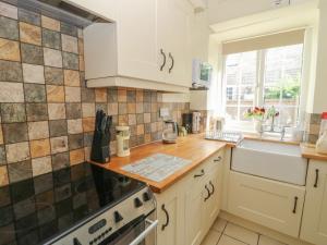 a kitchen with white cabinets and a counter top at Wedgewood Cottage in Leyburn