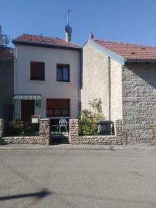 una casa blanca con una pared de piedra junto a una calle en Le Gîte de Ambre, en Grand