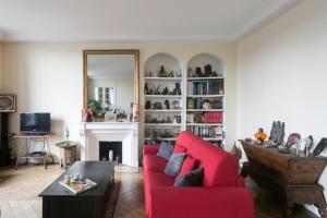 a living room with a red couch and a fireplace at Paris-sur-seine-chez-caroline in Paris