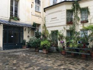 a courtyard with potted plants in front of a building at Paris-sur-seine-chez-caroline in Paris