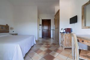 Habitación con cama, TV y suelo de baldosa. en Porto Giunco Residence, en Villasimius