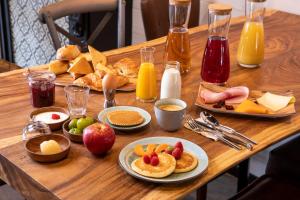 een houten tafel met borden met ontbijtproducten bij Cocoon inn in Cucq