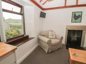 a living room with a chair and a fireplace at Kirkcarrion Cottage in Barnard Castle