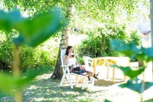 a woman sitting in a chair under a tree at B&b Villa Paradiso in Mezzana