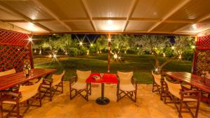 a patio with tables and chairs and a garden at night at Agroktima Elia in Nafplio