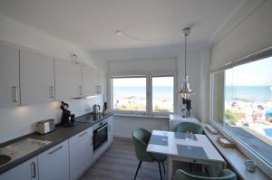 una cucina con armadi bianchi e tavolo con sedie di Schipperhus a Timmendorfer Strand