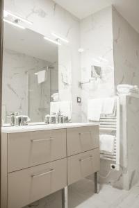 a white bathroom with a sink and a mirror at Hotel Les Galets in Criel-sur-Mer