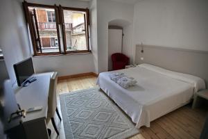 1 dormitorio con cama blanca y ventana en Albergo Accademia, en Trento