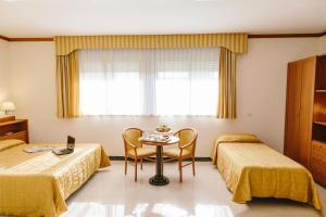 Habitación de hotel con 2 camas y mesa en Hotel Residence Federiciano, en Valenzano