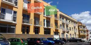 a large yellow building with cars parked in a parking lot at Apartments Alcalá Tenerife - Aloe & Cactus in Alcalá