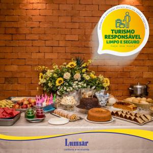 Hotel Lumiar في Coronel Fabriciano: طاولة عليها طعام وورود