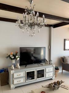 a living room with a television and a chandelier at Lalapanzi in Fish Hoek