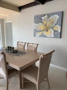 a dining room table with chairs and a painting on the wall at Lalapanzi in Fish Hoek