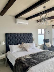 a bedroom with a large bed and a chandelier at Lalapanzi in Fish Hoek