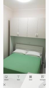 Schlafzimmer mit einem grünen Bett und weißen Schränken in der Unterkunft Raggio di sole in Rocca Imperiale