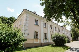 un gran edificio blanco con árboles delante de él en Nice Euapartments in the center, en Grodno