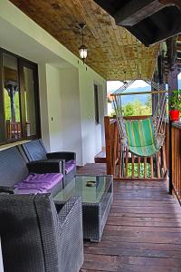 a porch with chairs and a hammock on a deck at GREEN HOUSE - Попниколови in Sapareva Banya