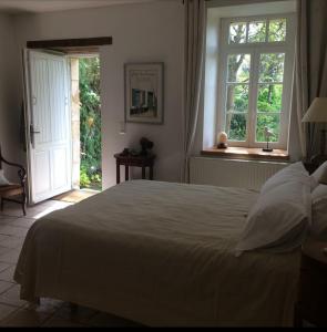 a bedroom with a large white bed and two windows at Chambre d'hôtes à Mignaloux-Beauvoir- le Thil in Mignaloux-Beauvoir