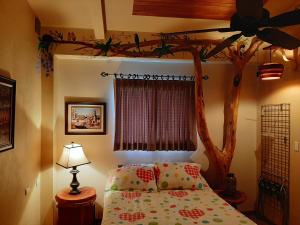 um quarto com uma cama temática de árvore e uma ventoinha de tecto em Marita's Bed and Breakfast em Nuevo Arenal