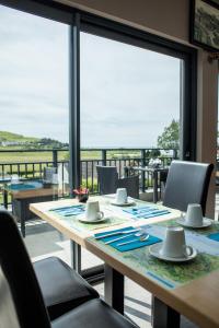 a dining room with a table with chairs and a large window at Hotel Les Galets in Criel-sur-Mer