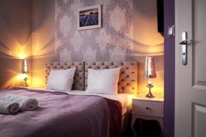 a bedroom with a purple bed with two lamps at Hotel Madelaine in Lwówek Śląski