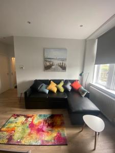 Ayr Riverside Apartments في آير: غرفة معيشة مع أريكة سوداء مع وسائد ملونة