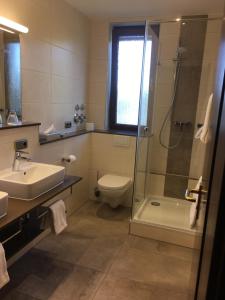 a bathroom with a shower and a sink and a toilet at Parkhotel Leiser in Planegg