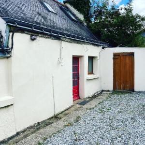 une porte rouge sur le côté d'une maison blanche dans l'établissement La Vieille Crêperie de Mangouëro, à Cléguérec