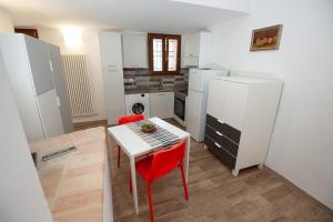 a kitchen with a white table and red chairs at Affittacamere degli Dei da Ico in Monzuno