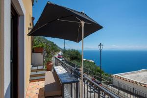 a black umbrella on a balcony with a view of the ocean at Golden Vaults Praiano in Praiano