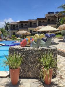 a group of statues sitting on a wall next to a pool at Pousada Enseada do Sol in Jacumã