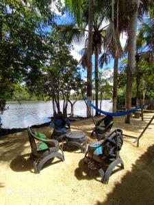 four chairs and a hammock on a beach near the water at Chalé Marinas in Barreirinhas