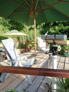 una cámara y sillas en una terraza con sombrilla en Stargazer Studio, en Saint-Chamassy